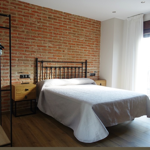 Habitación con cama de matrimonio y pared de ladrillo visto en la Casa Rural La Josefa, ubicada en Fermoselle, en pleno corazón de las Arribes del Duero.