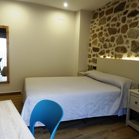 Habitación de matrimonio con pared de piedra, mobiliario de madera y ambiente rústico en la Casa Rural La Josefa de Fermoselle, ideal para disfrutar de las Arribes del Duero.