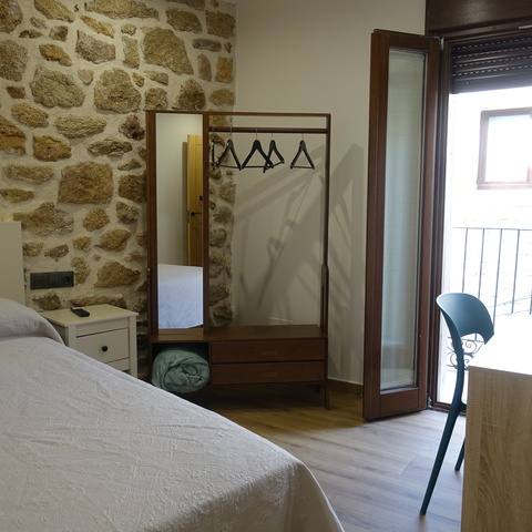 Habitación con cama de matrimonio, escritorio y balcón con luz natural, en los apartamentos rurales Casa La Josefa de Fermoselle, en pleno corazón de las Arribes del Duero.